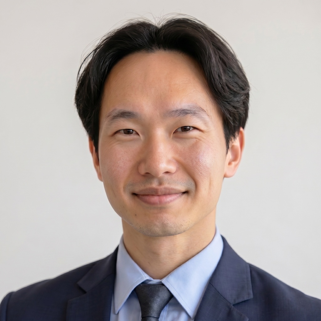 Close-up ERAS-style professional headshot of a well-groomed applicant wearing a matte navy blazer with clean shoulder fit, a crisp light blue collared shirt, and a solid dark tie, against a plain light background with soft even lighting.